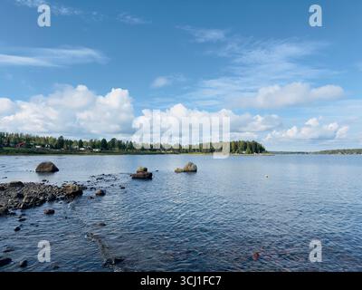 Ruhige Küstenlandschaft mit einer Insel mit üppigen Bäumen unter einem klaren blauen Himmel. Stockfoto