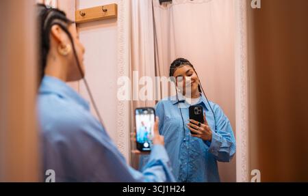 Selfie im Ankleidezimmer Eine junge Frau, die gerne andere Kleidung anprobiert Stockfoto