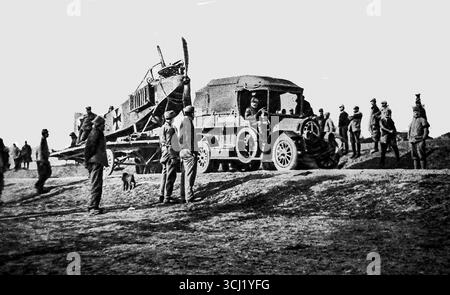 Dieses Foto von Le Miroir aus dem Jahr 1916 zeigt ein deutsches Flugzeug, das in Mazedonien gefangen genommen und von alliierten Truppen nach Salonika gebracht wurde. Umgeben von Soldaten wird das Flugzeug auf einen LKW geladen. Die Szene spiegelt den Zusammenbruch der deutschen Luftüberlegenheit auf dem Balkan und die strategische Bedeutung von Salonika als alliierter Stützpunkt wider. Das Bild unterstreicht die wachsende Rolle des Luftkampfes und des Transports von abgestürzten feindlichen Flugzeugen während des Ersten Weltkriegs Stockfoto