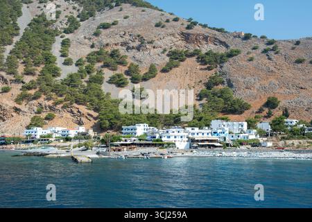 Agia Roumeli Dorf am Fuße der steilen zerklüfteten Berge entlang der Südwestküste der Insel Kreta, Griechenland. Blick vom Boot, das sich der Villa nähert Stockfoto