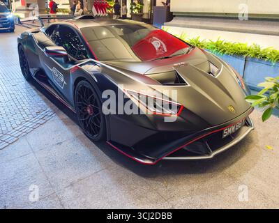 Eleganter schwarzer Lamborghini Huracan Sportwagen mit roten Details, der auf einer Straße in singapur unter hellen Lichtern geparkt ist Stockfoto