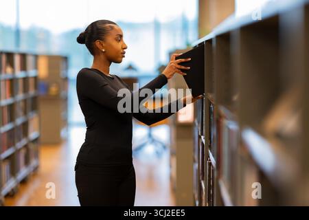 Schüler durchsuchen Bücher in einer Bibliothek Stockfoto