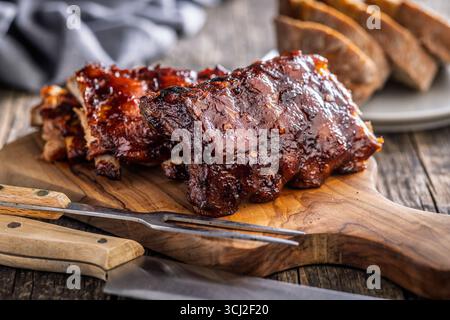 Glasierte Schweinerippen auf einem hölzernen Schneidebrett. Stockfoto