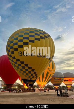 Luxor, Ägypten - 10. Februar 2025: Bunte Heißluftballons werden bei Sonnenaufgang aufgeblasen und bereiten sich auf einen Flug über das Niltal vor. Stockfoto