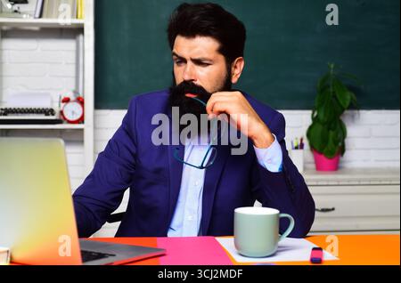 Nachdenklicher Student, der sich auf eine Prüfung oder Prüfung an der Universität vorbereitet. Lernen, Bildung. Nachdenklicher männlicher Schüler, der Notizen im Laptop macht. Ernsthafter Schullehrer Stockfoto