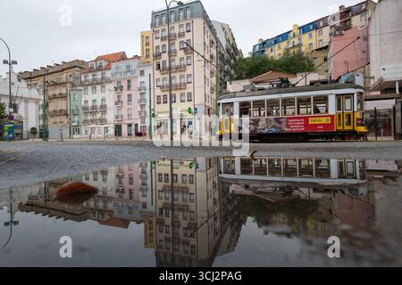 Eine atemberaubende Straßenaufnahme in Lissabon, Portugal, mit einer klassischen gelben Straßenbahn und einer Reihe von bunten Gebäuden. Die gesamte Szene wird in einem dargestellt Stockfoto