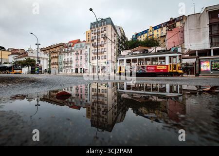 Eine atemberaubende Straßenaufnahme in Lissabon, Portugal, mit einer klassischen gelben Straßenbahn und einer Reihe von bunten Gebäuden. Die gesamte Szene wird in einem dargestellt Stockfoto