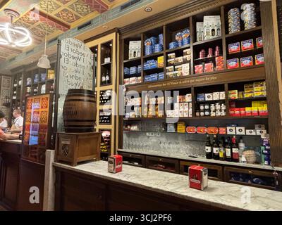 Gemütliches Interieur der traditionellen spanischen Tapas-Bar in Cadiz, mit Holztheken, hängenden Schinken, bunten Fliesen, kleinen Tellern und Wein. Stockfoto