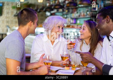 Eine freundliche, fröhliche Familie, die ein Treffen mit Gläsern und Bier in der Bar feiert. Hauptfokus genau in der Mitte Stockfoto