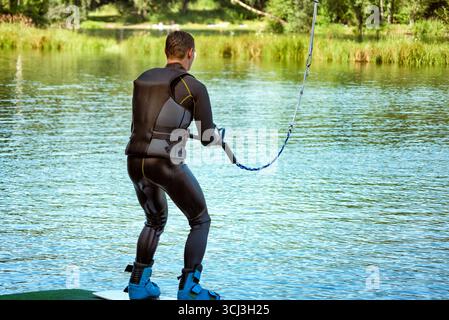 Ein Mann, bereit zum Wakeboarden auf einem See am Sommertag in einer Schwimmweste. Stockfoto