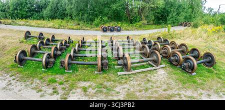 Aus der Vogelperspektive sind Radsätze aus Metall, Achsen für Lokomotiven, Zugwagen, die an einem verlassenen Bahnhof herumliegen Stockfoto