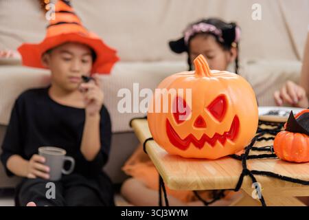 Kinder feiern mit Kürbissen und gruseligen Dekorationen am halloween-Tag. Ein Kind trägt einen Hexenhut Stockfoto