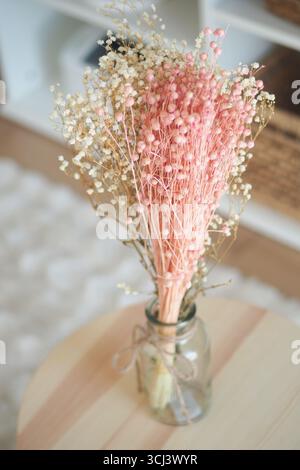 Getrockneter Blumenstrauß im Glasgefäß auf Holztisch Stockfoto