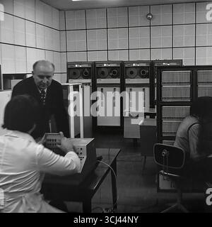 Ingenieure und Techniker warten im Januar 1978 einen großen sowjetischen Großrechner der es EVM-Serie in einem Rechenzentrum in einem Werk in Sloviansk. Das Archivfoto zeigt die Welt der Hochtechnologie in der Zeit der Stagnation und die Arbeit der wissenschaftlich-technischen Intelligenz. Diese Aufnahme, die das „Gehirn“ eines Industrieriesen erfasst, ist ein Symbol für das wissenschaftliche Potenzial und die friedliche Entwicklung des Donbass vor dem Krieg. Stockfoto