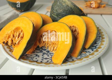 Stücke, Kürbisscheiben auf Porzellanplatte mit blauem Muster. Landwirtschaftliche Produkte und gesunde Ernährung. Küche und Hausmannskost. Stockfoto