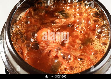 Nahaufnahme kochender koreanischer Kimchi-Eintopf oder Kimchi Jjigae auf Ttukbaegi Stockfoto