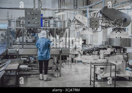 Ruhige Fabrik, wenige Werksarbeiter reinigen die Produktionslinie Förderband bereiten sich darauf vor, die Lebensmittelfabrik nachts zu schließen Stockfoto