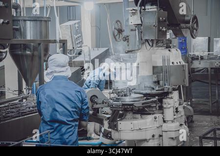 Ruhige Fabrik, wenige Werksarbeiter reinigen die Produktionslinie Förderband bereiten sich darauf vor, die Lebensmittelfabrik nachts zu schließen Stockfoto