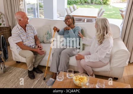 Ältere Freunde lachen und plaudern auf dem Sofa, genießen die gemeinsame Zeit zu Hause Stockfoto