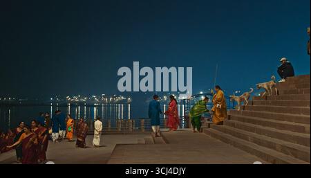 Varanasi, Uttar Pradesh, Indien - 6. Februar 2024: Menschen, die auf Uferdamm laufen, beleuchtet in den Dämmerungslichtern Stockfoto