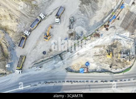 Luftaufnahme der Baustelle mit schweren Maschinen und Lkws inmitten von Erdarbeiten und provisorischen Bauwerken, Istanbul, İstanbul, Türkiye. Stockfoto