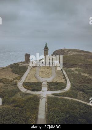 Der imposante Leuchtturm Cap Fréhel aus der Vogelperspektive steht am stimmungsvollen Himmel, ein Zeugnis für die Küstenstärke, Plévenon, Bretagne, Frankreich. Stockfoto