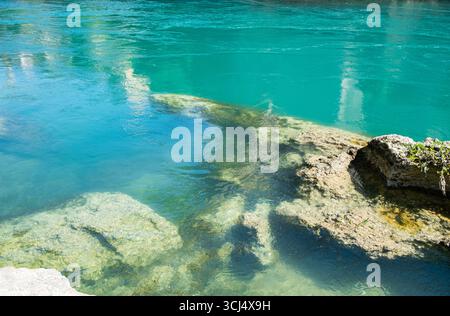 Klares türkisfarbenes Wasser fließt über das felsige Flussbett in Mostar, Bosnien und Herzegowina. Stockfoto