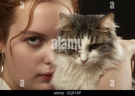 Ernste traurige junge Frau mit Down-Syndrom mit Katze, die in die Kamera schaut Stockfoto