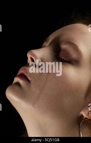 Traurige Frau mit geschlossenen Augen weinend, auf schwarzem Hintergrund, Nahaufnahme Porträt, Profilansicht Stockfoto