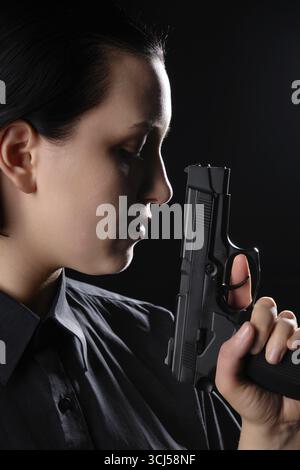 Weibliches Porträt mit Pistolennaht auf schwarzem Hintergrund Seitenansicht Stockfoto