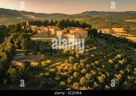 Panoramablick auf ein großes altes Anwesen auf einem Hügel mit Blick auf die Olivenhaine und Weinberge in der wunderschönen, im Spätsommer toskanischen Landschaft, Italien Stockfoto