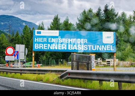 Unterquerung des Alpenhauptkamms. Hinweistafel an der Autobahn A 13 in Tirol auf die Baustelle des Brenner Basistunnels. Gries am Brenner Tirol Österreich *** Überquerung unter dem Alpenhauptkamm Wegweiser auf der A 13 in Tirol auf der Baustelle des Brenner Basistunnels Gries am Brenner Tirol Österreich Copyright: XRolfxPossx Stockfoto