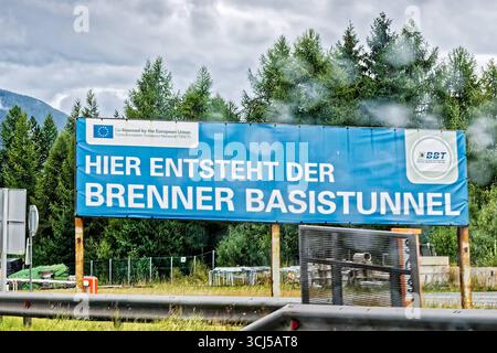 Unterquerung des Alpenhauptkamms. Hinweistafel an der Autobahn A 13 in Tirol auf die Baustelle des Brenner Basistunnels. Gries am Brenner Tirol Österreich *** Überquerung unter dem Alpenhauptkamm Wegweiser auf der A 13 in Tirol auf der Baustelle des Brenner Basistunnels Gries am Brenner Tirol Österreich Copyright: XRolfxPossx Stockfoto
