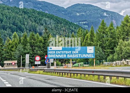 Unterquerung des Alpenhauptkamms. Hinweistafel an der Autobahn A 13 in Tirol auf die Baustelle des Brenner Basistunnels. Gries am Brenner Tirol Österreich *** Überquerung unter dem Alpenhauptkamm Wegweiser auf der A 13 in Tirol auf der Baustelle des Brenner Basistunnels Gries am Brenner Tirol Österreich Copyright: XRolfxPossx Stockfoto