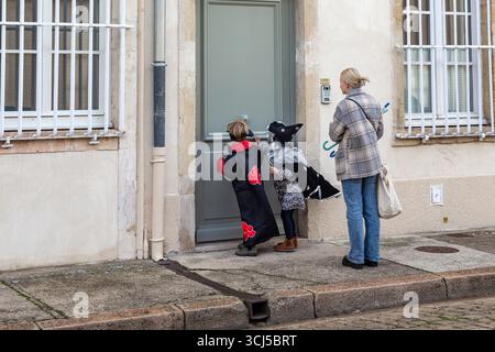 BEAUNE, FRANKREICH - 31. OKTOBER 2023: Dies ist eine unbekannte Frau mit Kindern in schicken Kleidern am Eingang zu einem Haus. Stockfoto