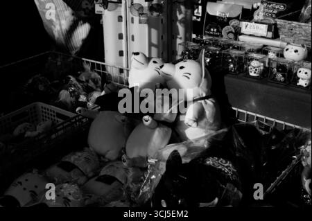 Plüschfüchspuppen und Glückskatzenfiguren in Schwarz-weiß an einem Straßenstand in Kyoto Stockfoto