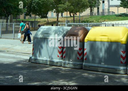 Viladecans. Barcelona - 05. September 2025: Ein paar Spaziergänge auf dem Bürgersteig an einem sonnigen Tag vorbei an einer Reihe von Behältern für das Recycling von Abfällen in Vilad Stockfoto