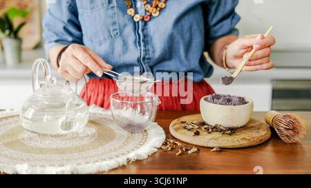 Eine Frau macht Blue Matcha Tee und siebt ihn durch Ein Sieb Stockfoto