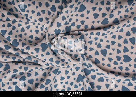 Weicher Stoff mit einem bezaubernden Muster aus blauen Herzen vor einem hellen Hintergrund, ideal für Valentinstag-Themen, Nähprojekte oder kreatives Design Stockfoto