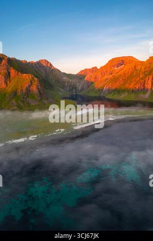 Luftaufnahme der niedrigen Wolken, die sich um die Stadt Eggum bei Mitternachtssonne im Sommer bewegen. Eggum Unstad, Vestvagoy Lofoten, Inseln, Norwegen, Europa. Stockfoto
