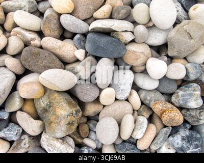 Verschiedene glatte Strandkiesel Svalbard Norwegen | HORNSUND, Svalbard — Eine nahe, texturierte Ansicht von abgerundeten grauen, hellbraunen und weißen Kieselsteinen an einem Strand in Hornsund, im Svalbard-Archipel, dem nördlichsten bewohnten Teil Europas. Die glatten, abgenutzten Oberflächen der Steine sind typisch für Kiesel, die durch Wellenbewegung und Schmelzwasser aus Gletschern entlang dieser norwegischen Arktis-Küste geformt wurden. Stockfoto