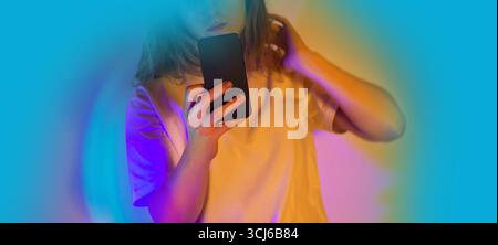 Frau, die ein Smartphone hält und online mit Neonlichtern chatten. Kommunikation in einem angenehmen Gespräch. Stockfoto