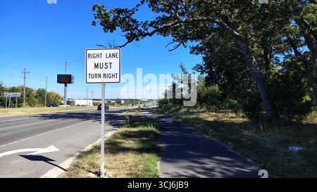 Eine amerikanische Autobahn mit einem Schild, das Bewegung und eine Rechtskurve anzeigt, eine leere Autobahn tagsüber mit Hinweisschildern und einem elektronischen Schild Stockfoto