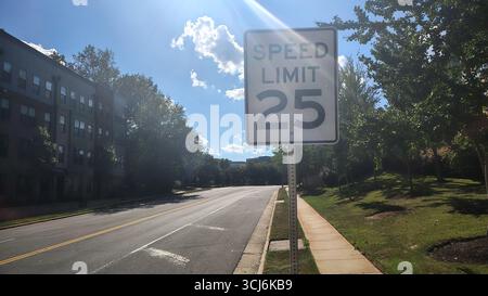 Ein Schild mit einer Geschwindigkeit von 25 km/h auf einer Straße zwischen einem Park und einem Wohnhaus in den Vereinigten Staaten an einem sonnigen Tag, amerikanische Verkehrsregeln Stockfoto