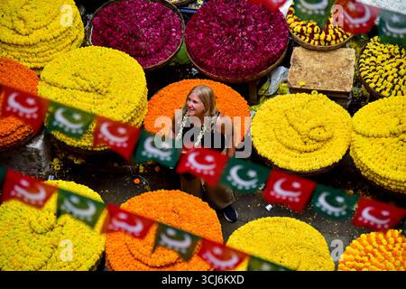 Bangalore, Karnataka, Indien. September 2025. Blumenhändler organisieren ihren bunten Bestand und warten am Freitag auf den Krishnarajendra Markt in Bengaluru. Im Volksmund bekannt als KR Market, ist er der größte Blumenmarkt der Stadt und einer der geschäftigsten in Südindien, wo täglich Tausende von Kilos Ringelblume, Jasmin, Rosen und andere Blüten gehandelt werden, insbesondere vor Festen und Hochzeiten. Ein ausländischer Besucher wird beobachtet, wie er die Blumen auf dem Markt bewundert, was die lebendige Szene noch verstärkt (Credit Image: © Shriram BN/ZUMA Press Wire). Nicht für kommerzielle ZWECKE! Stockfoto