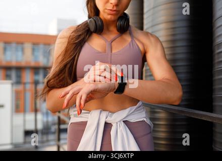 Nahaufnahme weiblicher Hände und Smartwatches. Abgeschnittener Schuss einer muskulösen Sportlerin, die ihren Puls überprüft. Stockfoto