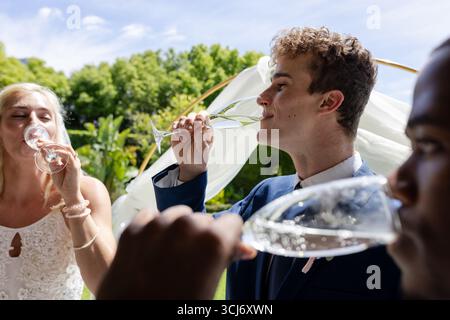 Gäste genießen bei der Hochzeitsfeier Champagner im Freien, lächeln und toasten Stockfoto