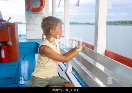 Kind, isst Sandwich auf einer Bootsfahrt in Vietnam, im Sommer Stockfoto