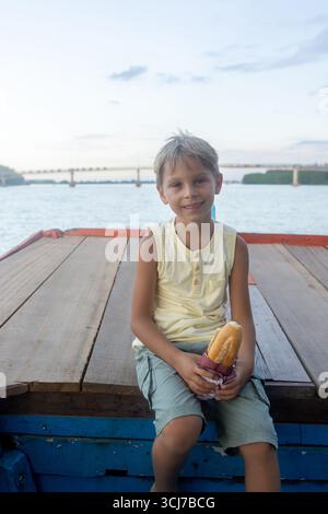 Kind, isst Sandwich auf einer Bootsfahrt in Vietnam, im Sommer Stockfoto