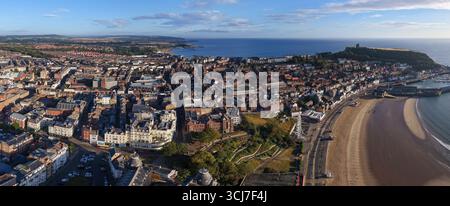 Panoramablick auf Scarborough am Morgen, mit dem breiten Sandstrand im Vordergrund, farbenfrohen Stadtgebäuden entlang der Promenade. Stockfoto